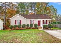 Tan house with red shutters, landscaping, and a red front door at 125 Havencrest Lndg, Garner, NC 27529