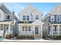 Charming two-story home features a welcoming front porch with blue door, manicured landscaping, and craftsman-style design at 1364 Barreto Dr, Wendell, NC 27591