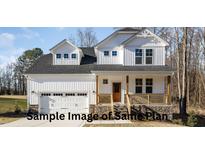 Two-story white house with stone accents, double garage, and a covered porch at 165 Tuskeegee Dr, Smithfield, NC 27577