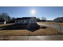 Newly constructed home with a gray exterior, landscaped yard, and driveway at 90 Faucette Dr, Selma, NC 27576