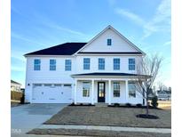 Two-story white house with a black door, two-car garage, and landscaping at 107 Barn Door Dr, Lillington, NC 27546