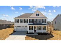 Charming two-story home featuring a covered porch, a two car garage, and a well maintained yard at 107 Barn Door Dr, Lillington, NC 27546