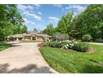 Beautiful home with a circular driveway and a lush, landscaped front yard with various plants and flowers at 12044 Iredell, Chapel Hill, NC 27517
