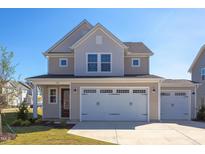 Two-story house with beige siding, white trim, and a three-car garage at 128 Baird Cv Ln, Angier, NC 27501