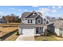 Two-story house with gray siding, white garage door, and landscaping at 86 Brooklynn Trl, Angier, NC 27501