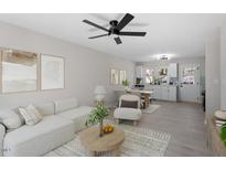 Open-concept living room with a ceiling fan, light gray walls, and a view of the adjacent kitchen and dining area at 1404 Valley Rd, Garner, NC 27529