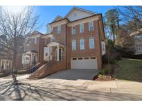 Brick three-story home with attached garage and steps leading to the front entrance at 255 Penley Cir, Raleigh, NC 27609