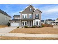 Two-story house with gray siding, white garage door, and rocking chairs on the porch at 3306 Longleaf Estates Dr, Raleigh, NC 27616