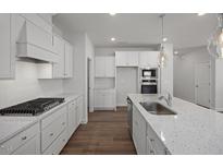 Modern kitchen featuring white cabinets, granite counters, stainless steel appliances, and a gas cooktop at 18 Fairwinds Drive Dr, Lillington, NC 27546