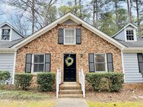 Charming brick home featuring black shutters, dormer windows, and a welcoming front door with a wreath at 103 Cimmaron Ct, Cary, NC 27511