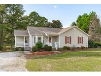 Beige house with red shutters, front porch, and landscaped yard at 120 Caribou Ln, Clayton, NC 27527