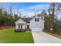 Newly constructed home with a gray exterior, stone accents, and a two-car garage at 138 Mayan Dr, Louisburg, NC 27549