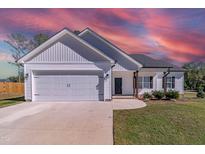 White farmhouse exterior with gray roof, two-car garage, and manicured lawn at 16 Sourgum Ct Ct, Zebulon, NC 27597