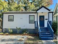 Charming white house with blue steps, landscaping, and gravel driveway at 1712 Rosetta Dr, Durham, NC 27701