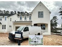 New construction home with white painted brick, black framed windows, and an attached two-car garage at 1725 Burnette Garden Path, Raleigh, NC 27612