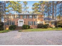 Brick two-story house with a gravel driveway and landscaping at 2700 Sherborne Pl, Raleigh, NC 27612