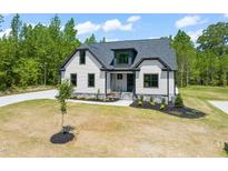 Charming home with white siding, black trim, and well-manicured landscaping in a beautiful tree-filled neighborhood at 320 Pilot Ridge Rd, Zebulon, NC 27597
