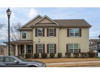 Two-story house with light beige siding, brown shutters, and a covered porch at 9306 Alcazar Walk, Raleigh, NC 27617