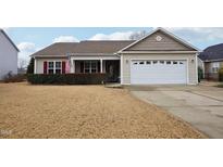 Tan house with red shutters, a white garage door, and a manicured lawn at 411 Joneshaven Dr, Fuquay Varina, NC 27526