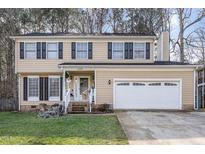 Two-story house featuring a beige exterior, a two-car garage, and landscaping at 6329 Dry Fork Ln, Raleigh, NC 27617