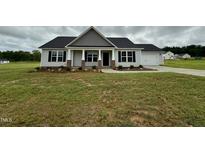 Charming single-story home featuring a covered front porch and attached two-car garage at 69 N Movado Trl, Kenly, NC 27542