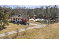 Aerial view of charming red house with pond and wooded area at 8437 Charlie Stovall Rd, Oxford, NC 27565