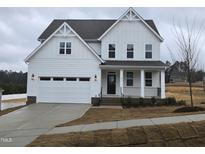 Two-story farmhouse-style home with white siding, a black door, and a two-car garage at 1013 Prominence Dr., Homesite 22, Durham, NC 27712
