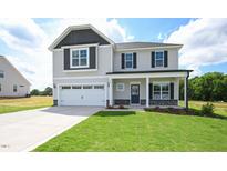 Charming two-story home with a manicured lawn, two-car garage, and inviting front porch at 223 Johnson Ridge Way, Four Oaks, NC 27524