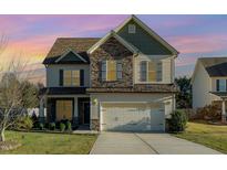 Charming two-story home featuring a stone facade, attached two-car garage, and well-maintained lawn at 2407 Cattail Pond Dr, Zebulon, NC 27597