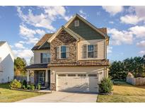 Charming two-story home with a mix of stone and siding, well-manicured lawn, and an attached two-car garage at 2407 Cattail Pond Dr, Zebulon, NC 27597