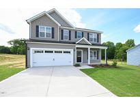 Charming two-story home with a covered front porch, two-car garage, and a well-manicured front lawn at 247 Johnson Ridge Way, Four Oaks, NC 27524