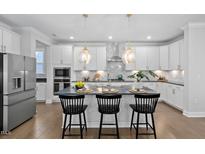 Modern kitchen with island, stainless steel appliances, and white cabinets at 2923 Heirloom Way, Apex, NC 27502