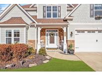 Charming home featuring a covered front entrance with stone accents, rocking chairs, and a well-manicured lawn at 347 Country Mill Way, Fuquay Varina, NC 27526