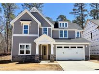 Charming two-story home with a blend of gray siding, stone accents, and a white garage door at 9164 Dupree Meadow Dr # 14, Angier, NC 27501