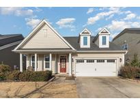 Charming home featuring a 2-car garage, red front door and manicured landscaping at 120 Martingale Dr, Holly Springs, NC 27540