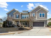Two-story home with gray siding, stone accents, and a three-car garage at 1819 Capstone Dr, Durham, NC 27713