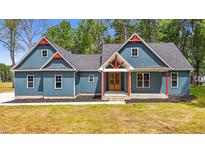 Beautiful blue home with red accents, a covered front porch, black mulch, and a lush green lawn at 260 Ellington Rd, Graham, NC 27253