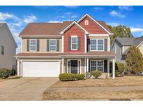 Two-story house with red and tan siding, a white garage door, and a well-maintained lawn at 339 Leyland Cypress Ln, Fuquay Varina, NC 27526