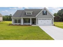 Charming gray home featuring a two-car garage, well-manicured lawn, and traditional architectural details at 6294 River Rd, Fuquay Varina, NC 27526