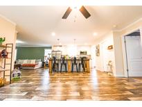 Spacious open-concept living area with a modern kitchen island and wood-look vinyl flooring at 979 Natchez Trce, Fuquay Varina, NC 27526