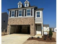 Beautiful new construction home with two-car garage, brick accents, gray siding and dormer windows at 1125 Channel Drop Lp, Zebulon, NC 27597