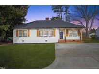 Charming renovated ranch home with a white exterior, updated landscaping, and a spacious driveway at 306 W Lee St, Mebane, NC 27302