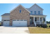 Charming two-story home featuring a brick facade, three-car garage, and inviting front porch at 54 Cultivator Ct, Angier, NC 27501