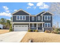 Two-story house featuring gray siding, stone accents, and a three-car garage at 6217 Adcock Rd, Holly Springs, NC 27540