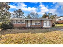 Brick ranch home with gray trim, covered porch, and well-maintained lawn at 704 Sunnybrook Rd, Raleigh, NC 27610