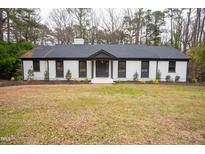 Charming brick home with black trim, a manicured front lawn, and mature trees at 72 Beverly Dr, Durham, NC 27707