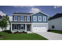 Two-story house with blue and gray siding, white garage door, and landscaping at 157 Grove Township Way, Angier, NC 27501