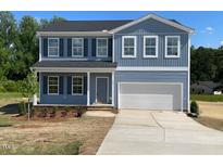 Charming two-story home featuring blue siding, a two-car garage, and a well-maintained front yard at 157 Grove Township Way, Angier, NC 27501