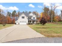 Two-story house with a gray roof and beige siding, a two-car garage and a landscaped yard at 1726 Rapids Ct, Franklinton, NC 27525