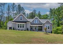 Charming gray home with stone accents, manicured lawn, and lush landscaping provides beautiful curb appeal at 3925 Cedar Knolls Dr, Youngsville, NC 27596